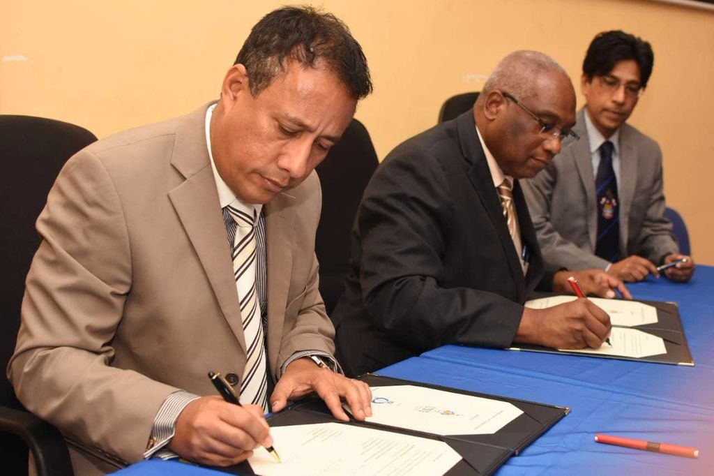 Police Commissioner Gary Griffith, left, and principal of UWI, St Augustine, Professor Brian Copeland sign the MoU.