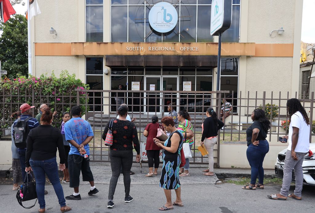 People wait in line outside the National Insurance Board in San Fernando to apply for salary relief grants yesterday.