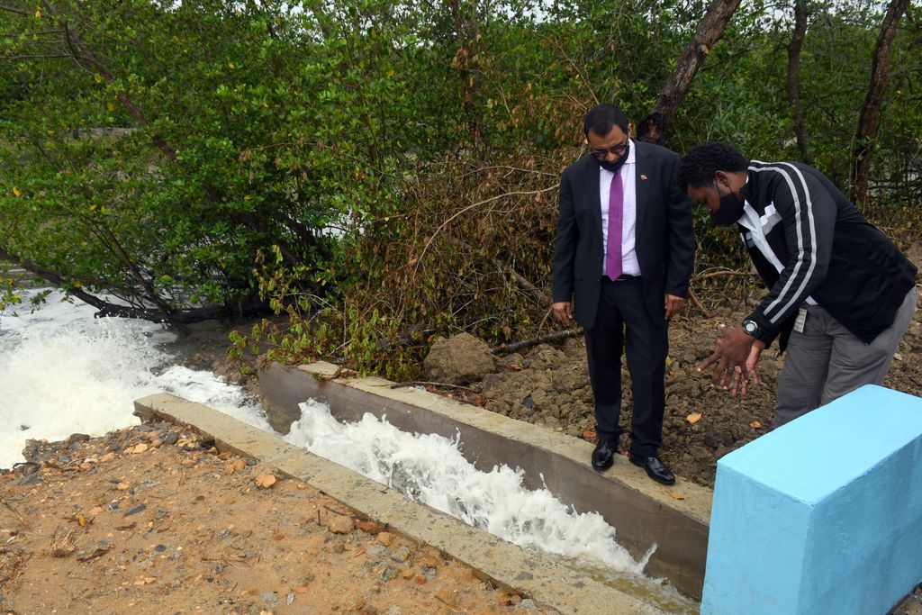 Works and Infrastructure Minister Rohan Sinanan , left, and  Drainage Superintendent with the Drainage Division Patterson Dick,look at the output of the pump, where the overflow was pumped into the Cunupia River at Cacandee Road, Felicity, yesterday. 