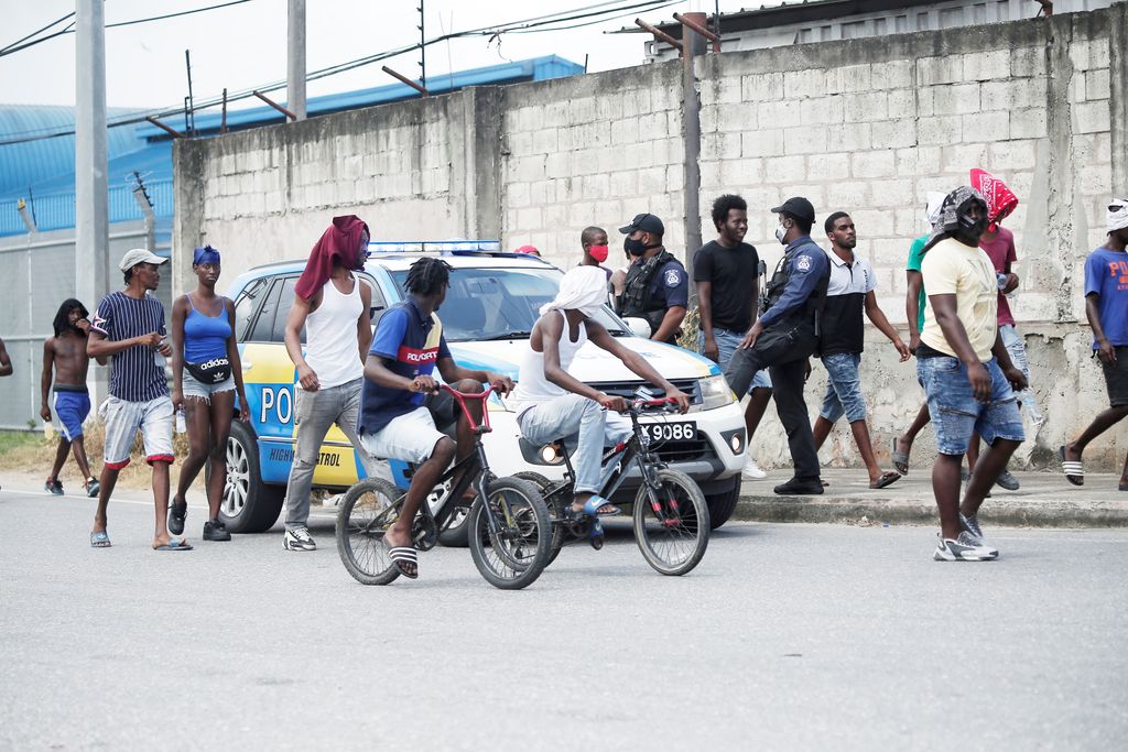 A group of residents from Beetham Gardens walk past police officers along the Beetham Highway as they make their way into Sea Lots, Port-of-Spain yesterday.
