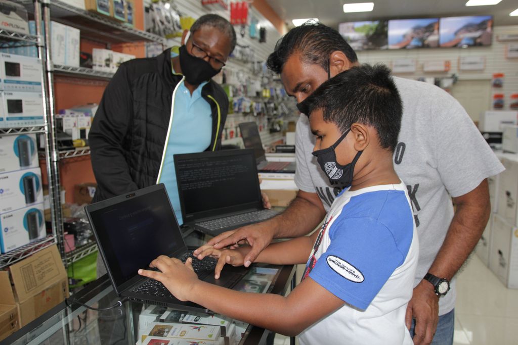 Naveed Mohammed checks out a new Dell laptop with his father Shameed Mohammed, assisted by The Wizz Computers store technician Kevin Victory at the store’s Pennywise Plaza, Chaguanas branch yesterday.