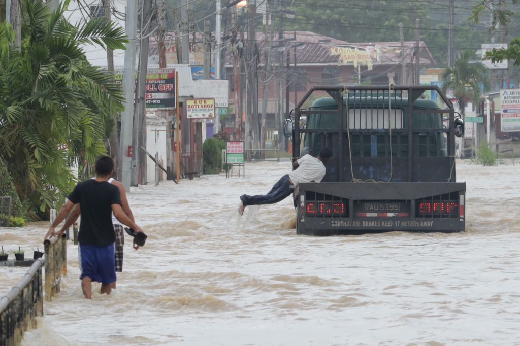  A man jumps onto a passing truck as he tries to hitch a ride out of flood waters along Penal Rock Road, Penal, yesterday.  