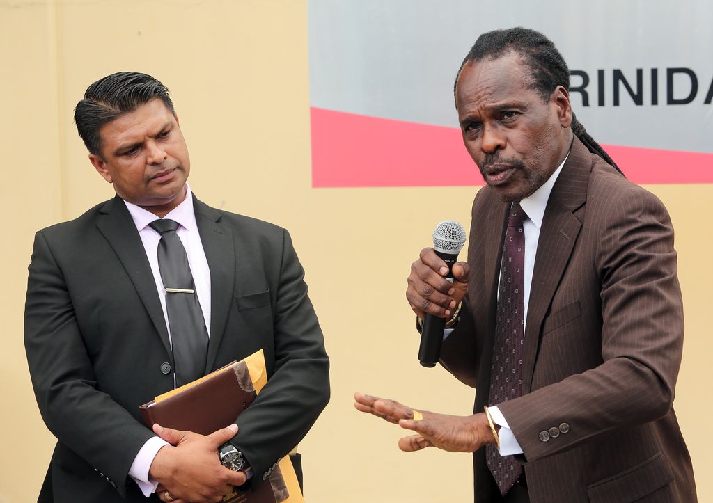 Minister of National Security Fitzgerald Hinds, right, answers questions from journalists during a media conference outside the Forensic Science Centre, St James, yesterday. Looking on is Senior Superintendent Rishi Singh, of the Homicide Bureau Region 2. 