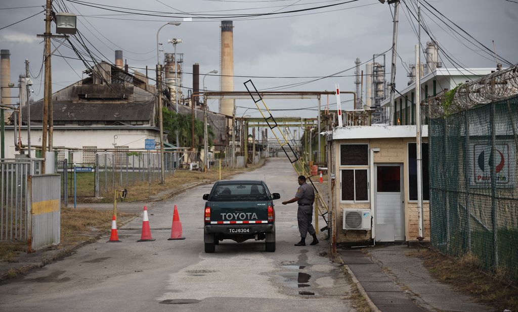 File: A security officer checks the driver of a vehicle entering the refinery in Pointe-a-Pierre.