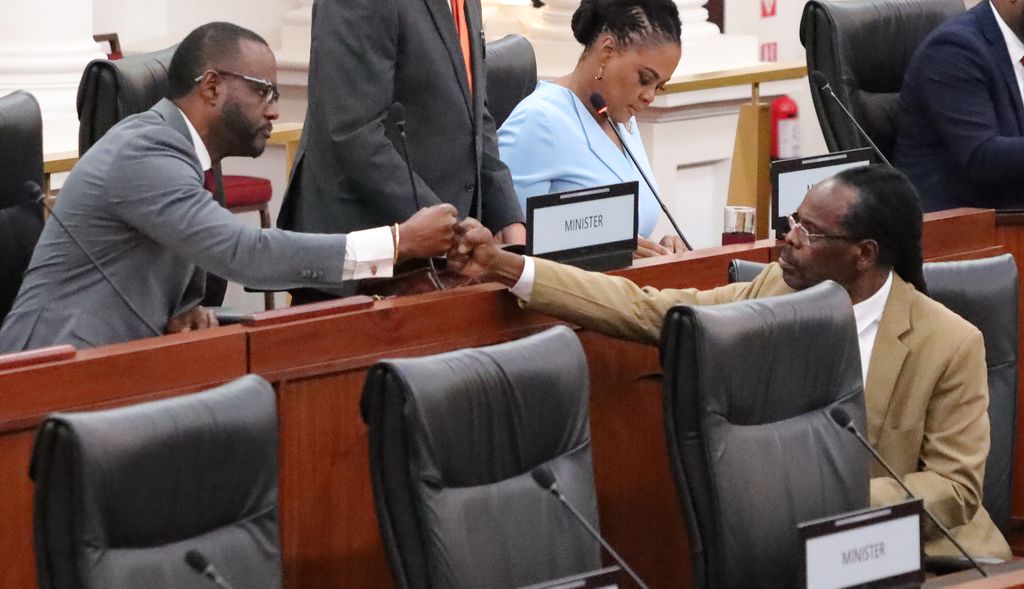 Public Utilites Minister Marvin Gonzales, left, gives a bounce to National Security Minister Fitzgerald Hinds during yesterday's sitting of the Senate.