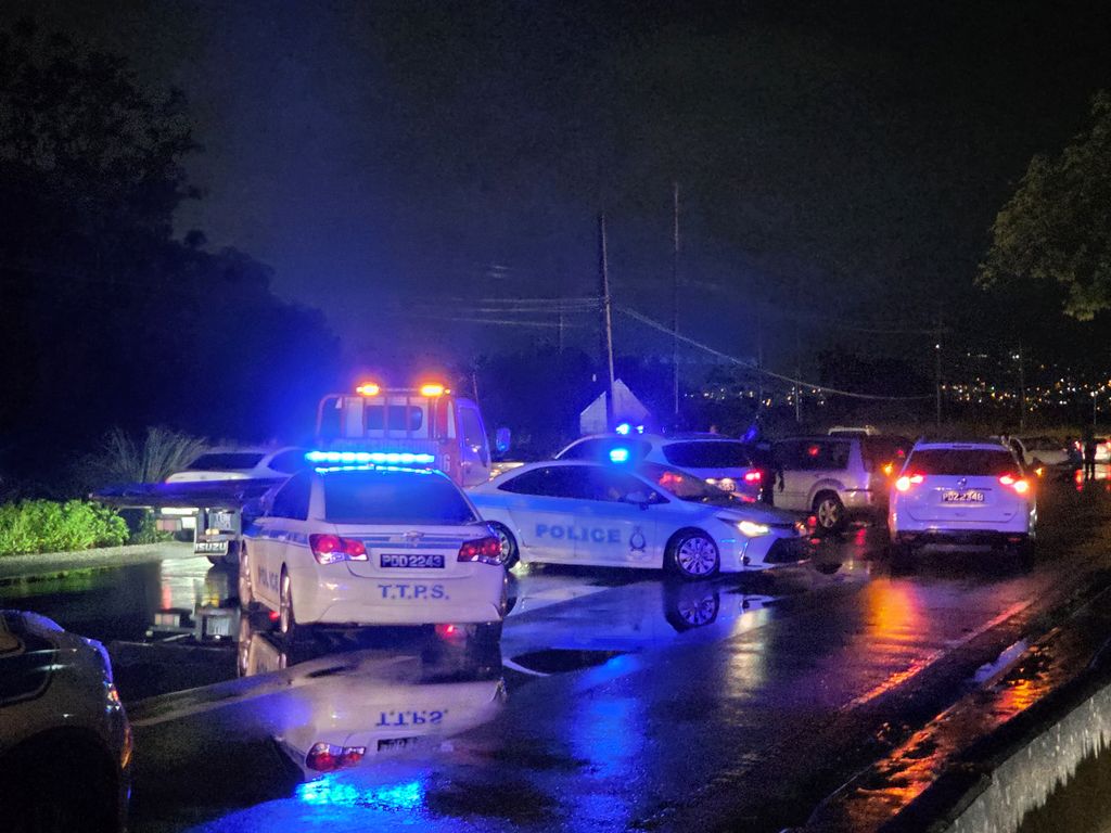 Police at the scene where a vehicle crashed on the Churchill Roosevelt Highway, following the shooting of prison officer Govindra Balgobin along Orange Grove Road, Arouca, on June 20.