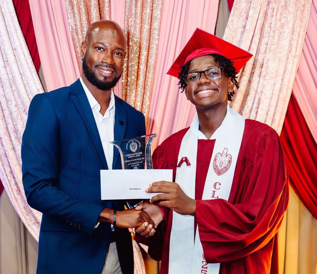 Nevin Roach presents the award to Kai Caruth at his graduation ceremony.