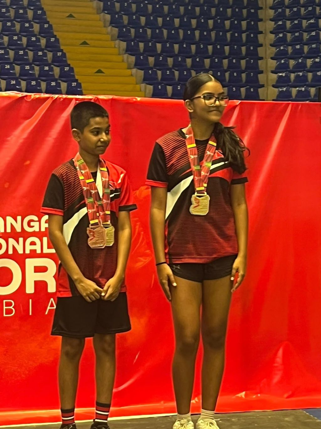 Liam Rajkumar and Asia-Lee Waller wearing their badminton medals in Colombia